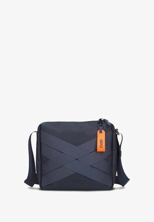 Navy crossbody bag made of fabric with textured straps and a bright orange tag, featuring a zip closure and adjustable strap.