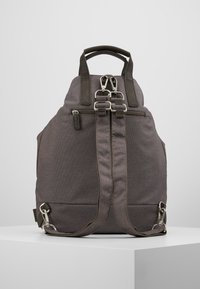 Mochila de tela gris con acentos de cuero, asas superiores dobles y tirantes ajustables. Cuenta con dos cremalleras y herrajes metálicos en los laterales.