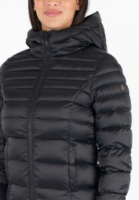 Zwarte pufferjack met een rits aan de voorkant, capuchon en een quiltontwerp met horizontale stiksels. Bevat een klein logo op de linkerschouder.