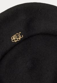Čierny plstený barete s ohnutým tvarom, ktorý má na boku pripevnenú zlatú brošňu s logom "BBL". Mäkká textura, klasický dizajn.