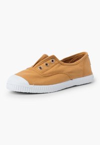 Chaussure slip-on en toile jaune moutarde avec semelle en caoutchouc blanc, sans lacets, et trois œillets en métal sur le dessus pour la ventilation.