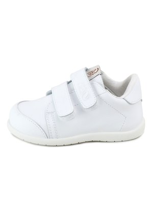 Zapatilla blanca de caña baja con dos tiras de velcro, cuello acolchado suave y suela de goma texturizada, vista de lado.