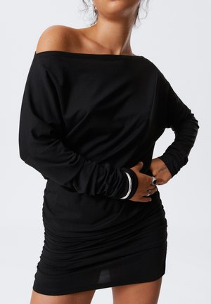 Robe noire décolletée avec des manches longues, présentant une texture plissée et des accents argentés aux poignets. Tissu lisse et léger.