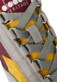 Sneaker Adidas Heritage con un upper in suede giallo, lacci grigi e accenti color borgogna, con occhielli argentati e una suola in gomma testurizzata.
