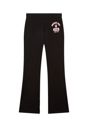 Zwarte flared broek van rekbare stof. Kenmerkt een roze grafische print op de heup met tekst: "AMERICAN MADE 213 JUICY."