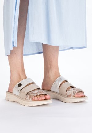 Sandales à enfiler avec une base beige, des brides gris clair et des accents floraux. Matériaux doux avec une finition текстurée et une semelle rembourrée.