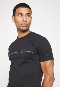 Calvin Klein Jeans REPEAT LOGO TEE UNISEX - T-shirt estampada - black