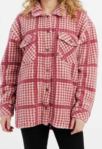 Vaaleanpunavalkoruudullinen fleece-paitatakki, jossa on kaksi rintataskua ja ruskeat napit. Takissa on pehmeä pinta ja rento istuvuus.