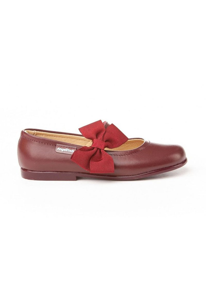 Zapato plano de cuero burdeos para niña con un lazo de tela a juego en el lateral y una pequeña etiqueta de la marca cerca del talón.