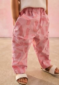 Pantalons cargo roses en tissu léger, ornés d'un motif abstrait dans des nuances variées de rose, avec deux poches latérales et une taille élastique.