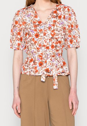 Bloemenwikkelblouse met korte pofmouwen, met oranje, bruine en paarse patronen op een lichte achtergrond, gestrikt in de taille.