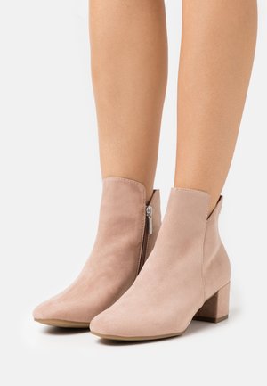 Helle rosa Wildleder-Stiefeletten mit Blockabsatz, seitlichem Reißverschluss, spitzer Zehenform und Ausschnittdetail am Knöchel.