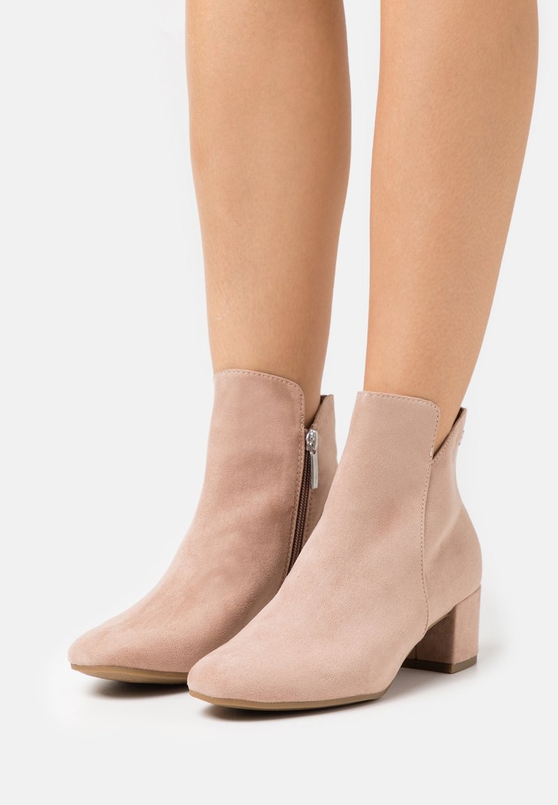 Helle rosa Wildleder-Stiefeletten mit Blockabsatz, seitlichem Reißverschluss, spitzer Zehenform und Ausschnittdetail am Knöchel.