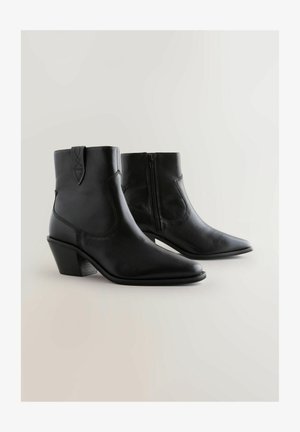 Bottines en cuir noir avec un bout pointu, une fermeture éclair sur le côté et un talon courbé. Comprend des détails cousus et une finition lisse.