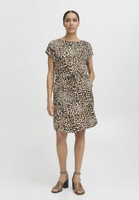 Leopardmönstrad klänning i lätt tyg, korta ärmar, smal midja med dragsnöre, knälång, i kombination med bruna klacksandaler.