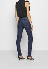 Smala mörkblå jeans i denim, med midja i normalhöjd, fem fickor och en diskret söm som går längs med sömmarna.