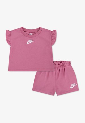 Ensemble Nike rose taille tout-petit comprenant un haut à manches courtes volantées et un short à taille élastique, les deux avec des logos Nike blancs.