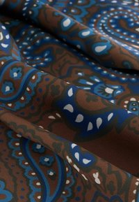 Textiel met een bruine basis en ingewikkelde blauwe, witte en zwarte paisleypatronen. De stof heeft een gladde textuur en een vloeiende uitstraling.
