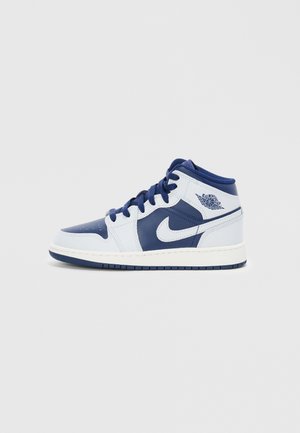 Biało-granatowy sneaker Air Jordan 1 o średnim kroju, z logo Nike swoosh i logo skrzydeł Air Jordan na jednolitym tle.