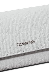 Witte gestructureerde portemonnee met een patroon op het oppervlak, voorzien van een zilveren Calvin Klein-logo aan één zijde. Glad materiaal met een rechthoekige vorm.