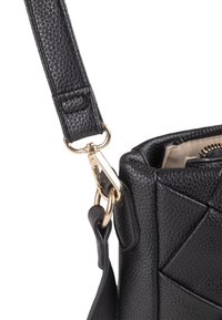 Schwarze, strukturierte Handtasche mit einem Clip und einem Riemen in Goldfarbe. Verfügt über geometrische Nähte am Körper und ein glattes Innenfutter.