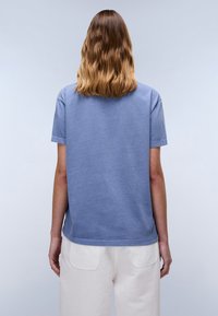 Blauwe katoenen t-shirt met korte mouwen, een relaxte pasvorm en een ronde halslijn, gecombineerd met witte broek met achterzakken.