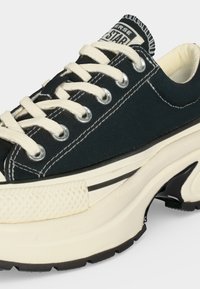 Μαύρο καμβά Converse sneaker με λευκά κορδόνια, παχιά λευκή σόλα με κυματιστό σχέδιο και ορατό λογότυπο "Converse All Star" στη γλώσσα.