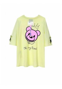 Camiseta amarilla de manga corta con un gran gráfico de oso rosa y el texto "Oh my Chaei". Adornada con acentos verdes en las mangas.