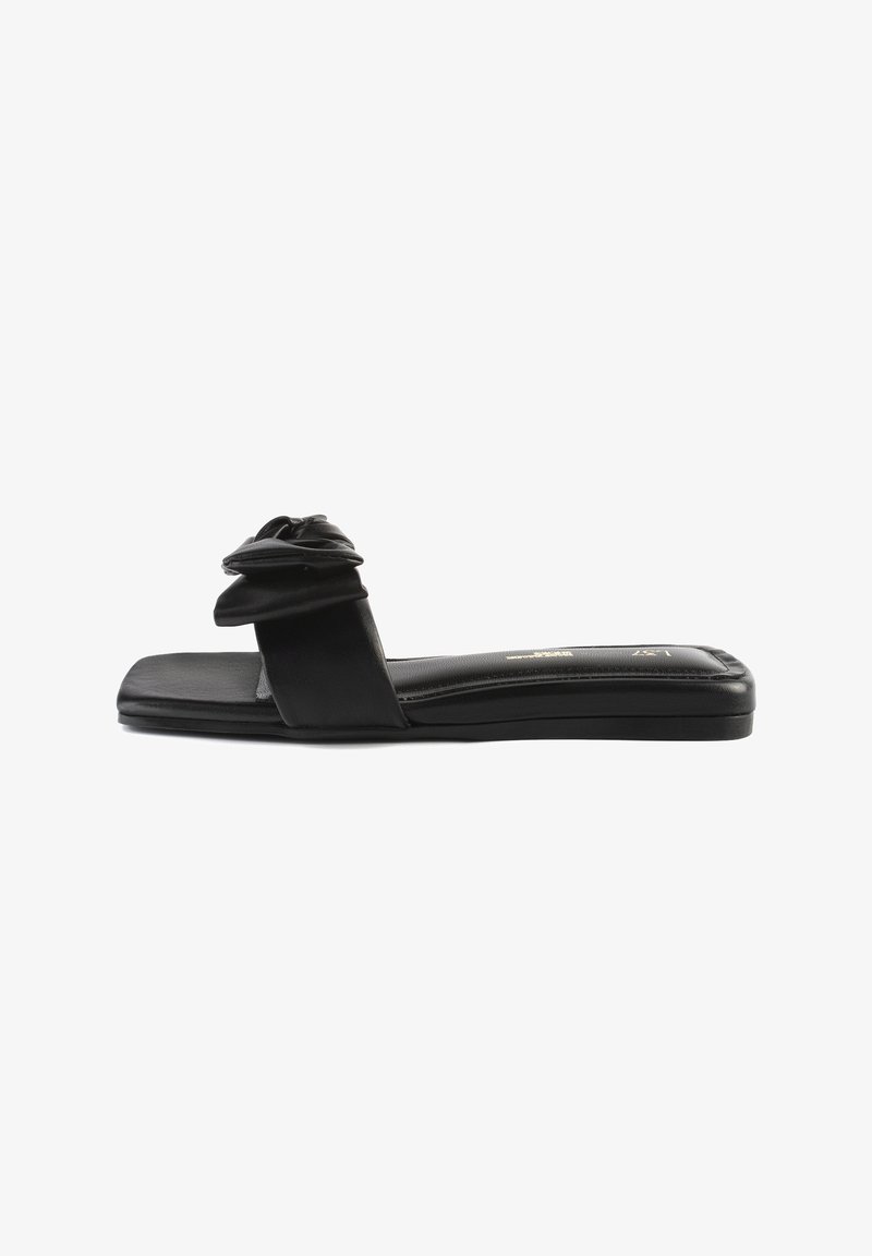 Sandales plates noires avec une texture en cuir lisse, une forme de bout carré et un détail de nœud en tissu sur la sangle pour un design supplémentaire.