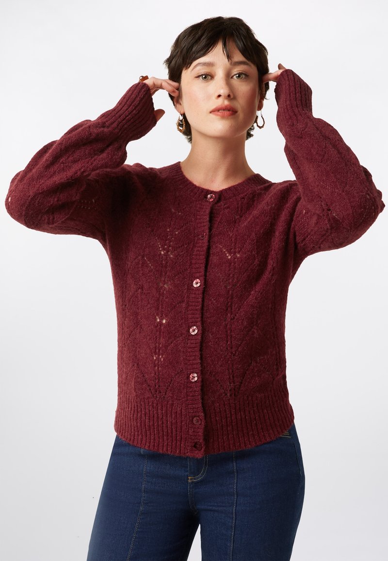 Cardigan en maille bourgogne avec un motif de diamants texturé, des poignets côtelés et cinq boutons avec des accents roses. Manches longues et encolure arrondie.