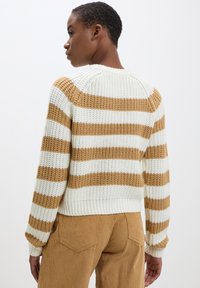 Maglione lavorato a maglia con strisce alternate in crema e marrone. Design croppato con orlo a coste e tessuto texturizzato. Maniche lunghe.