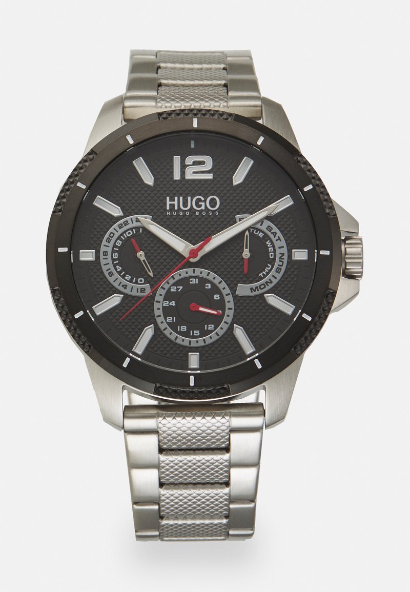 Orologio Hugo Boss con un quadrante nero texturizzato, dettagli argentati, lancetta dei secondi rossa e un cinturino in acciaio inossidabile a rete. Include visualizzazioni della data e del giorno.