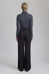 En långärmad, figurn�ära grå topp med hög krage, i kombination med vida, randiga svarta byxor. Slät tygtextur och skräddarsydd design.