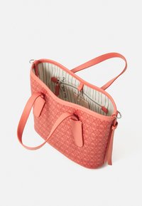 Coral fabric handbag with embossed pattern, two handles, and a lined interior featuring a zipper pocket and striped design.