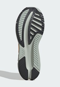 Running shoe sole with a black rubber outer layer, textured grooves, and light green base for cushioning. Features a rounded heel design.