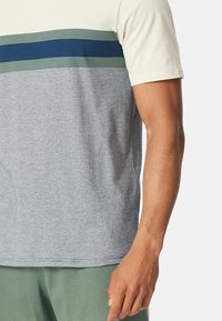 T-shirt gris à manches courtes avec une section supérieure crème et des rayures horizontales bleu et vert ; en coton, design ajusté, col rond.