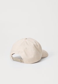 Beige verstellbare Baseballmütze mit Kunststoff-Druckknopfverschluss, sechsseitigem Design und Belüftungsöffnungen auf einem weißen Hintergrund.