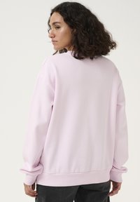 Felpa rosa chiaro con maniche lunghe, polsini a costine e scollo rotondo. Texture liscia e vestibilità comoda. Design semplice, senza fantasie.