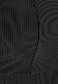 Material negru cu textură striată, arătând o prim-planare a texturii, cu linii verticale și o suprafață netedă, având un detaliu curbat al cusăturii.