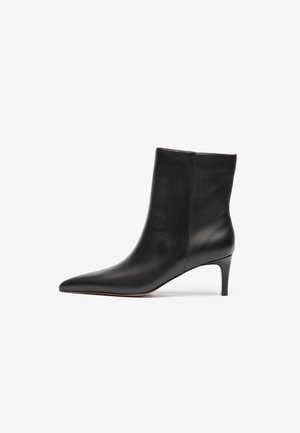 Bota de cano baixo em couro preto com bico fino e salto esbelto, apresentando uma textura suave e design elegante.