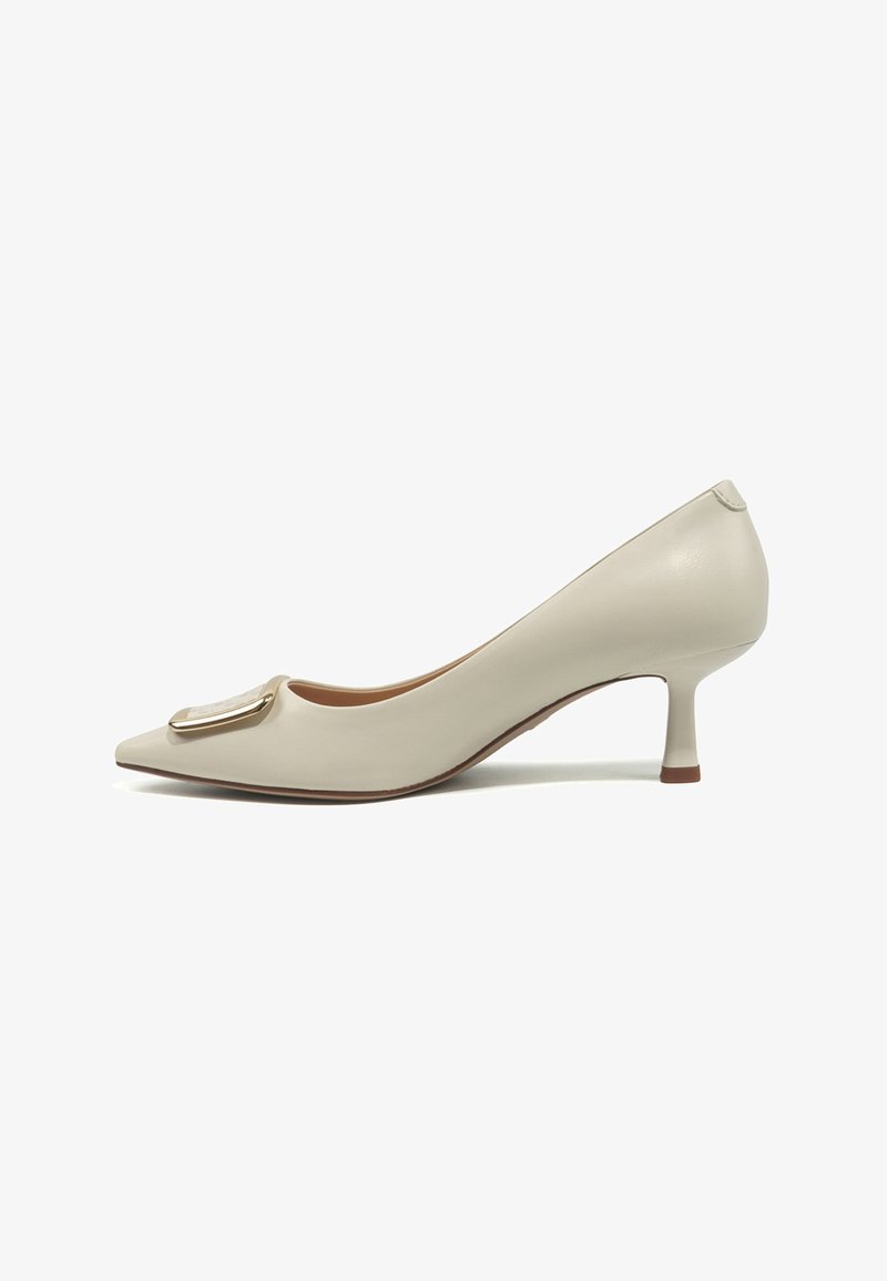 Beige pumps med spids tå, lav hæl og en dekorativ spænde med guldkant foran samt en slank, mellemhøj hæl.