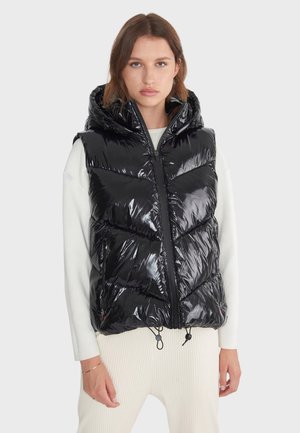 Zwarte puffer vest met een glanzende afwerking, ritssluiting en een capuchon. Kenmerkt zich door chevron-stiksel en verstelbare koorden aan de onderkant.