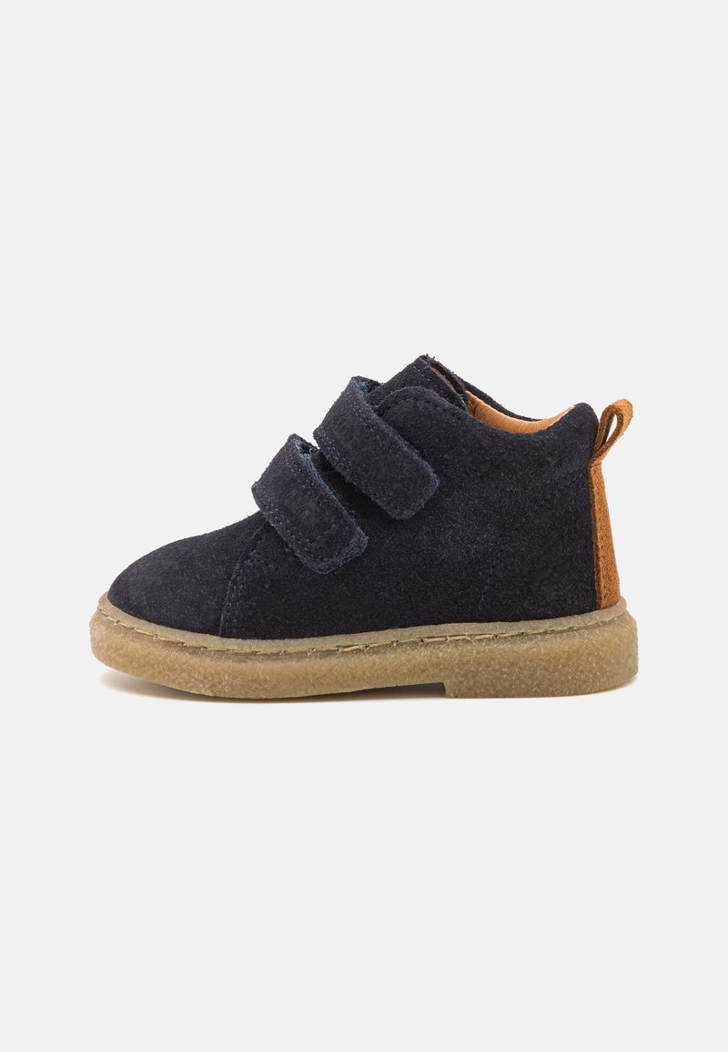 Stivaletti in suede blu navy per bambini con due cinturini in Velcro regolabili, con schienale in pelle beige e suola in gomma; forma corta e arrotondata.