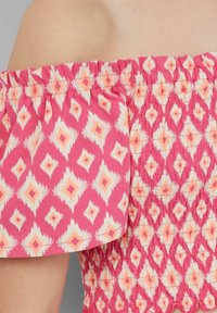 Rosa schulterfreies Oberteil mit geraffter Textur. Verfügt über ein Diamantmuster in Pfirsich und Creme, mit Rüschenärmeln und elastischem Bund.