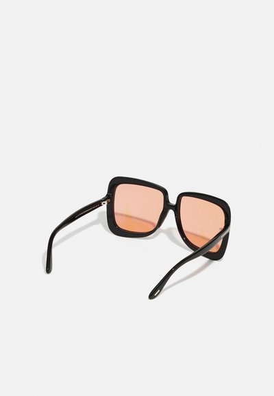 Μαύρα τετράγωνα γυαλιά ηλίου με ροζ φακούς, διαθέτοντας παχιά γυαλιστερά σκελετά και λεπτούς μαύρους βραχίονες. Σχεδιασμένα με διακριτές μεταλλικές λεπτομέρειες.