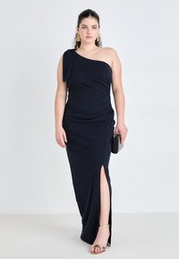 Navy blue one-shoulder dress in stretch fabric with a side slit, featuring a draped design and a tied accent at the shoulder.