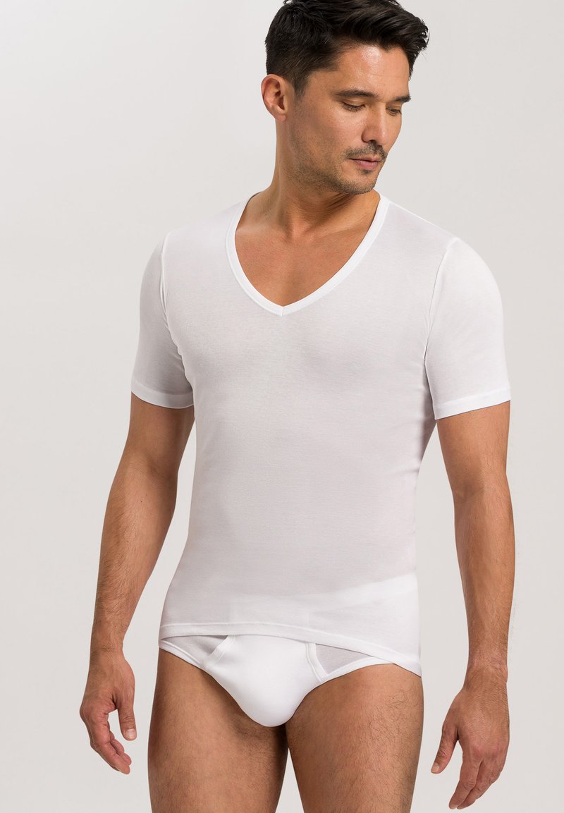 Weißes kurzes T-Shirt mit V-Ausschnitt aus glattem Stoff, taillierter Schnitt, leichtes Material, kombiniert mit weißen figurbetonten Slips.