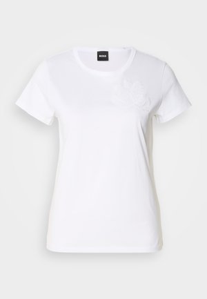 T-shirt bianco in cotone con maniche corte. Presenta un ricamo floreale tono su tono sul lato sinistro del petto. Design classico con collo a giro.