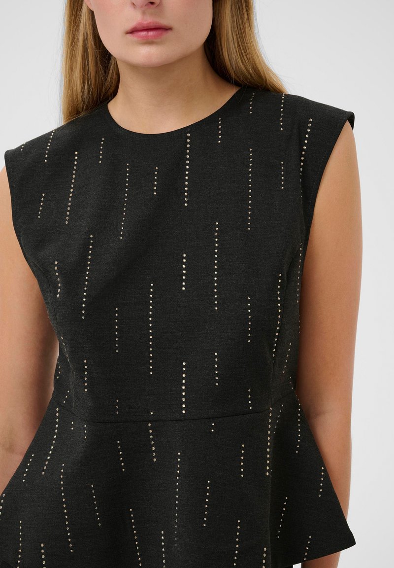 Top peplum en tela negra con una textura sutil y clavos dorados verticales dispuestos en un patrón lineal. Diseño sin mangas.