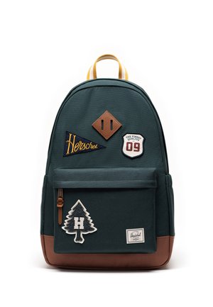 Mørkegrøn rygsæk med brune detaljer, gult håndtag og broderede mærker, herunder "Herschel", nummer 09 og et træ med "H."